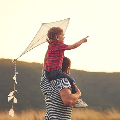 Private Client image - girl sitting on fathers shoulders with a kite