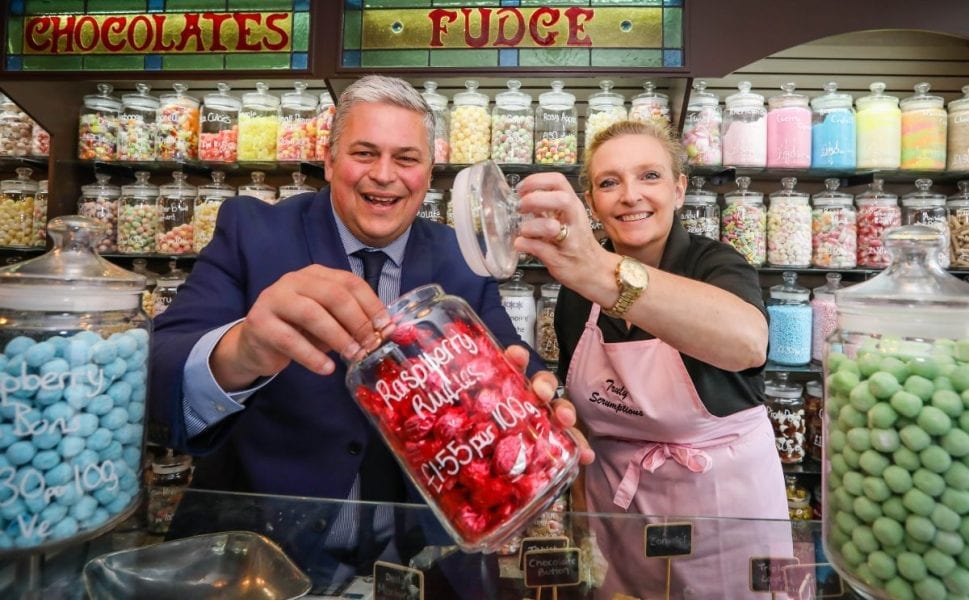 man and woman at sweet shop counter opening jar