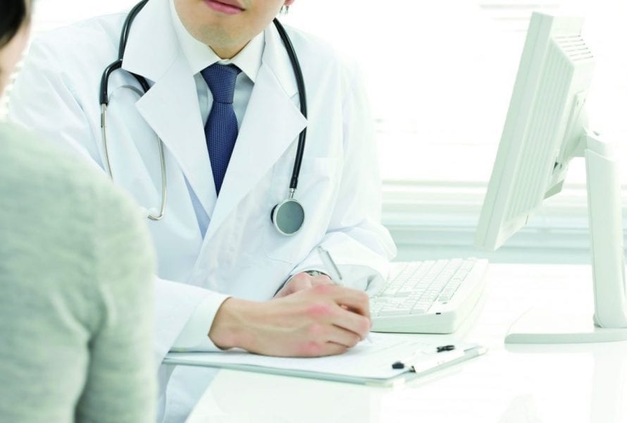 doctor sat at desk writing note to patient