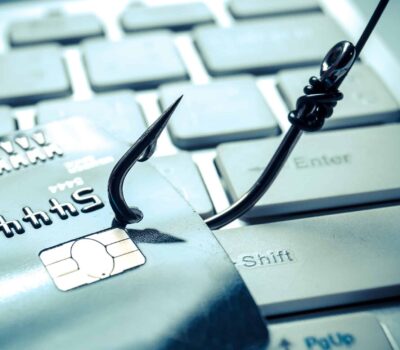 A Fishing Hook Catches A Credit Card On A Computer Keyboard To Symbolise Financial Phishing Scams.