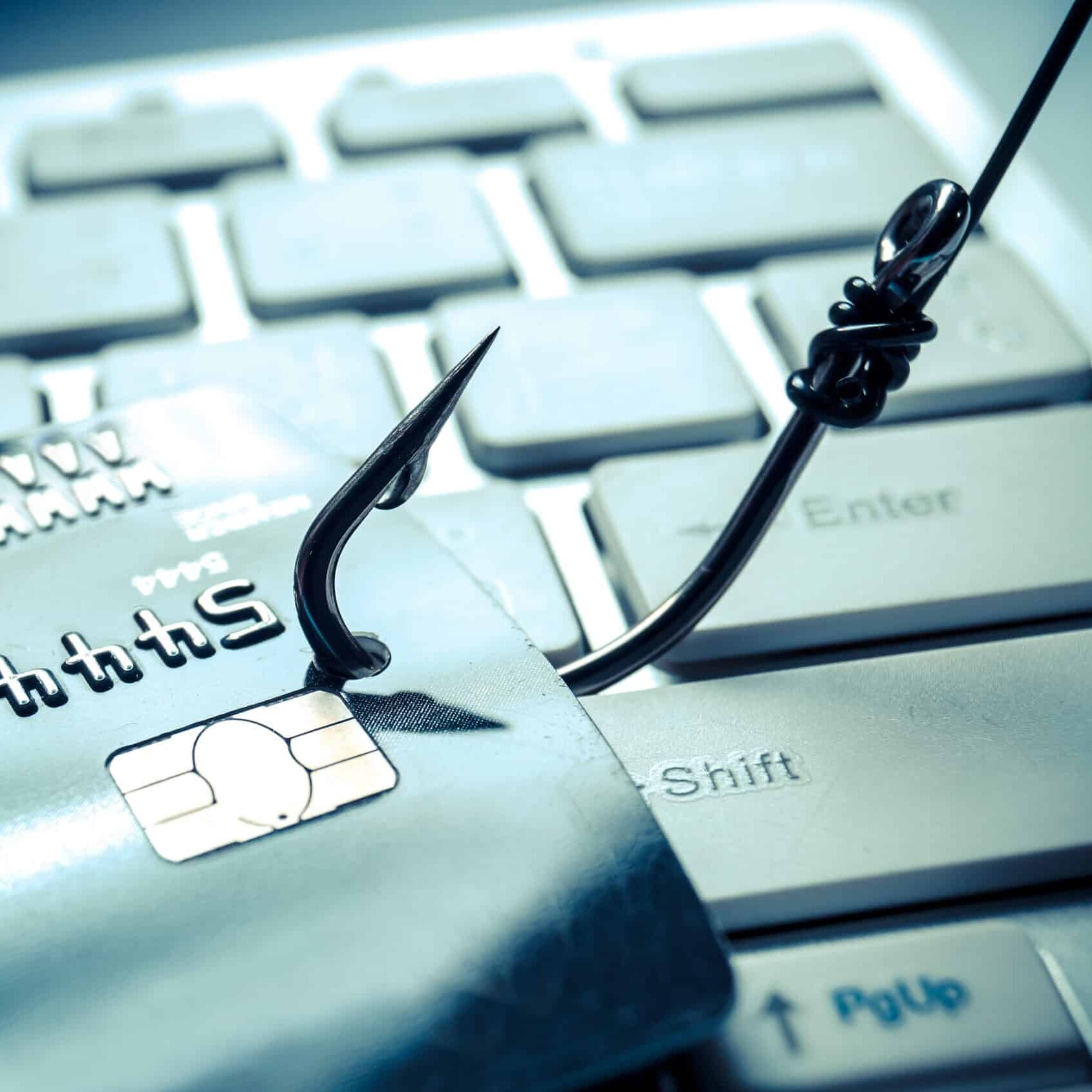 A fishing hook catches a credit card on a computer keyboard to symbolise financial phishing scams.